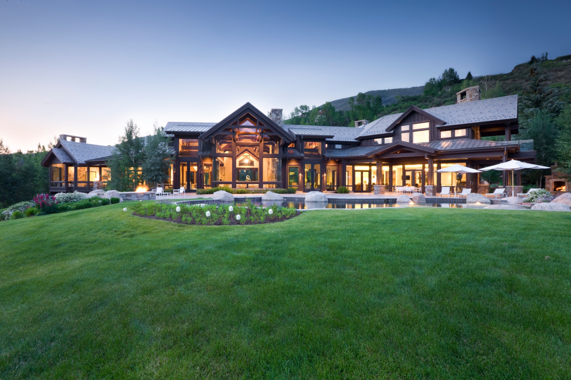 Timber-framed estate at dusk with pool and manicured gardens